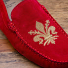 Red loafer with gold embroidery on a wooden surface