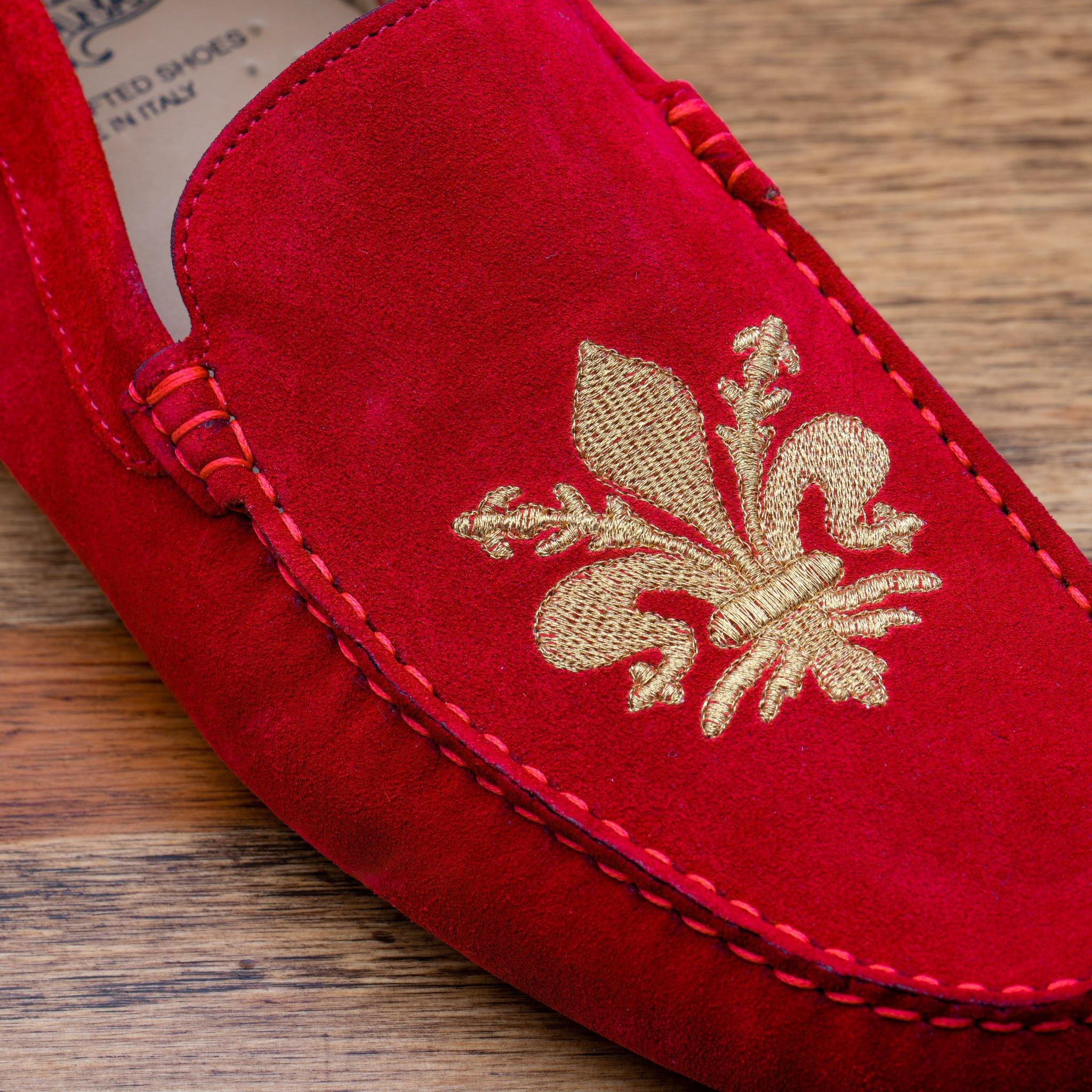 Red loafer with gold embroidery on a wooden surface