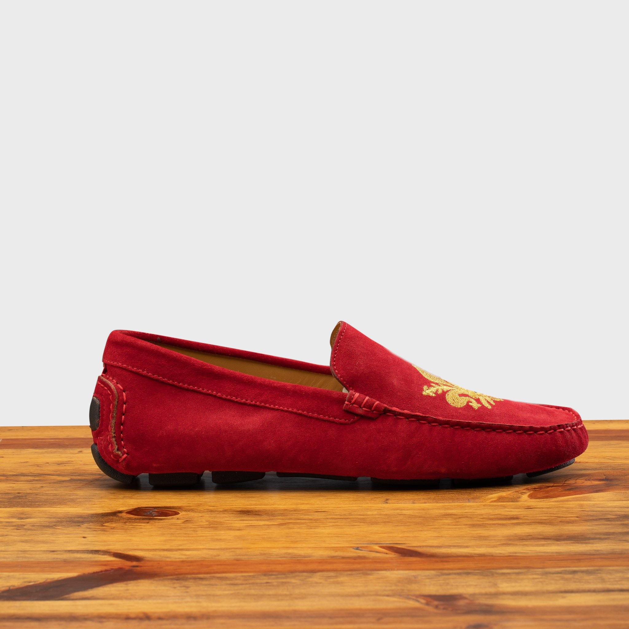 Red loafer with gold embroidery on a wooden surface