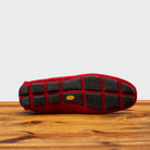 Outsole of Red loafer with gold embroidery on a wooden surface