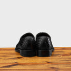 A Pair of Black woven dress shoe on a wooden surface with a light gray background