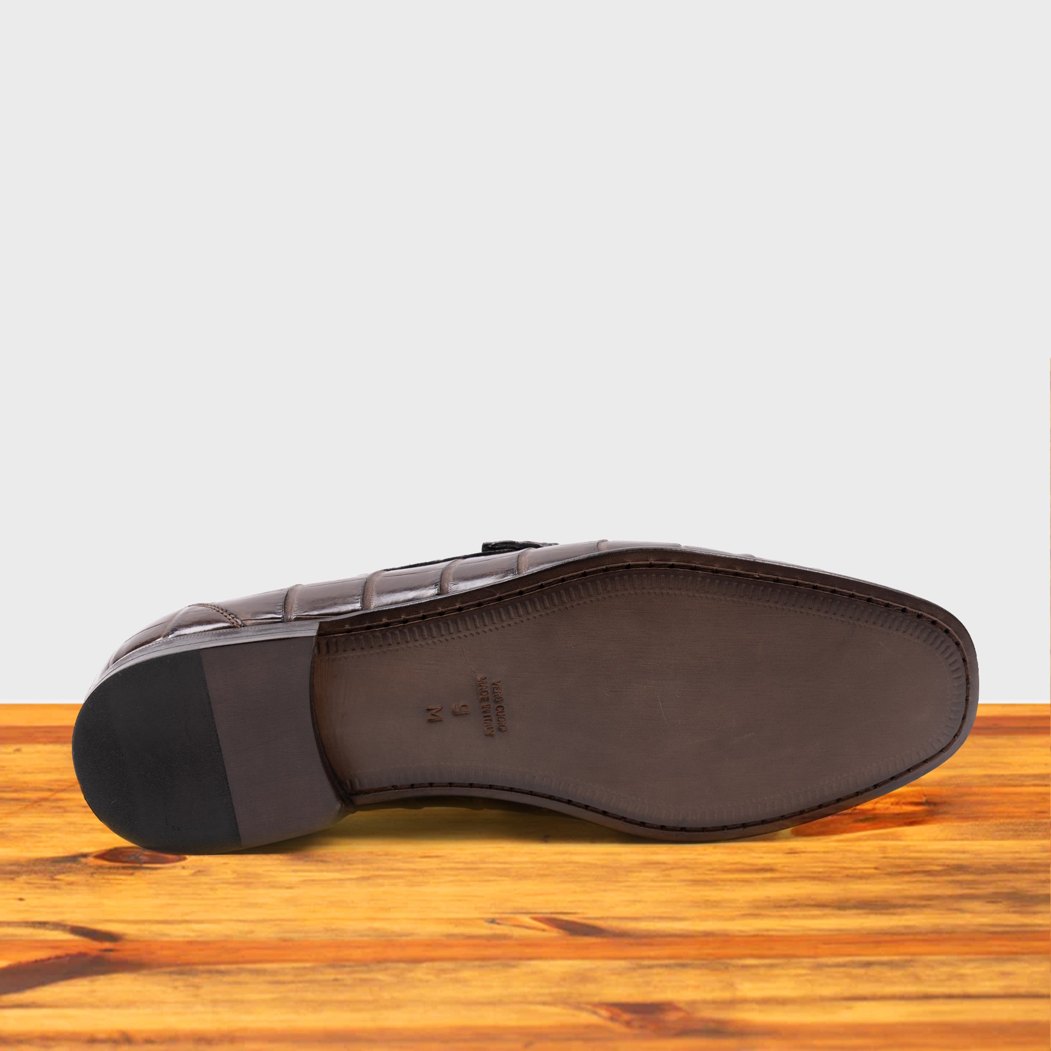 Outsole of Moor crocodile-patterned loafer on a wooden surface with a light gray background