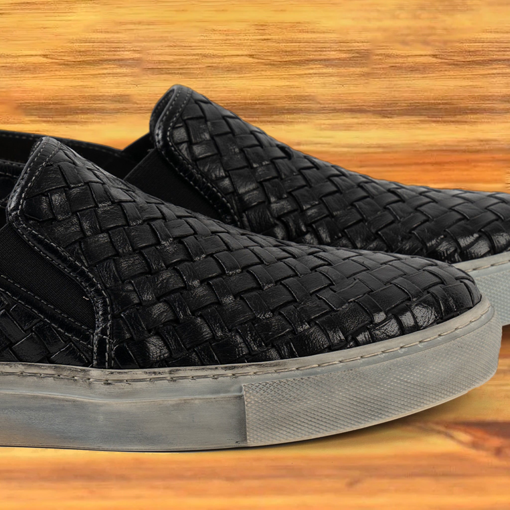 A Pair of black woven slip-on shoe on a wooden surface