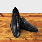 Pair of Black leather shoe on a wooden surface with a light gray background