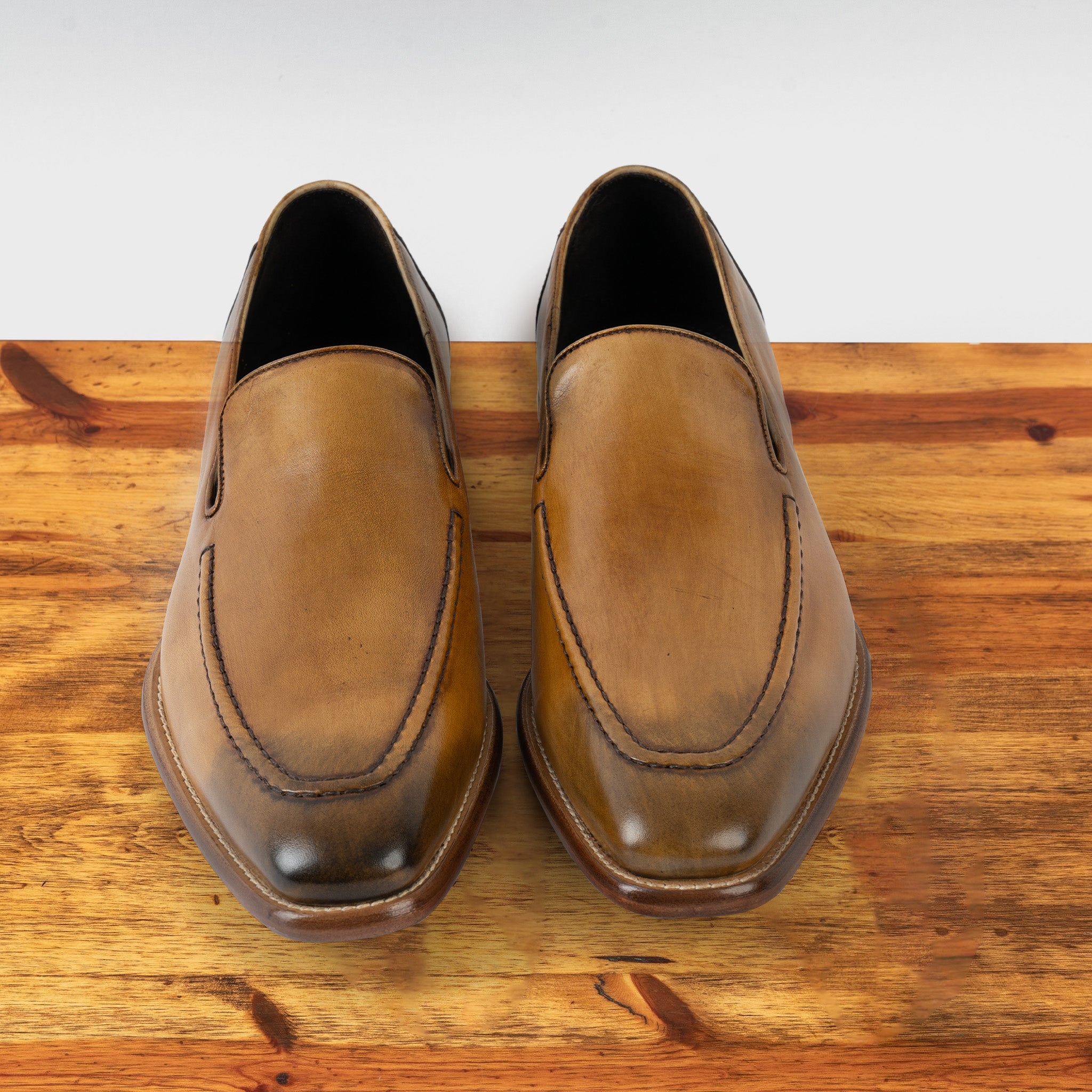 A Pair of Spice leather loafer on a wooden surface with a light gray background