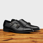 A Pair of  black leather shoe with Double buckle on a wooden surface