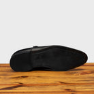Outsole of black leather shoe with Double buckle on a wooden surface
