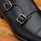 Black leather shoe with Double buckle on a wooden surface