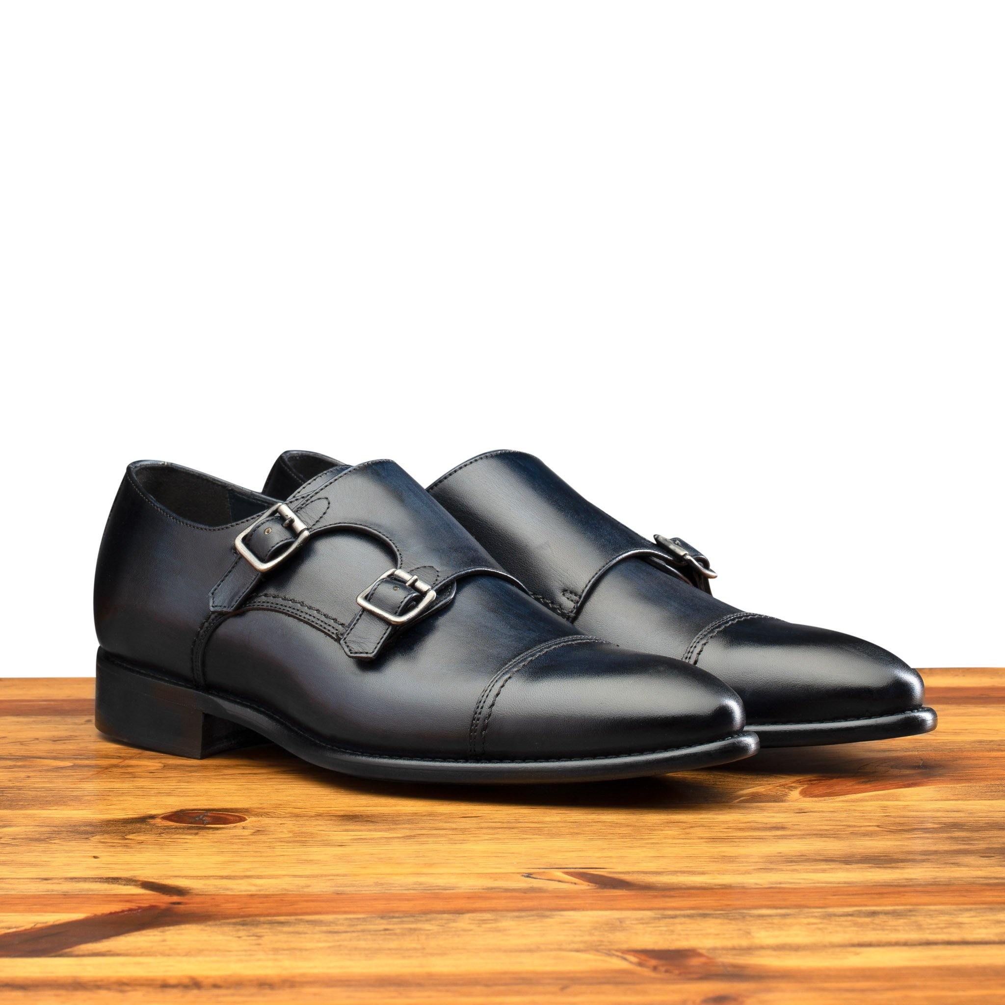 A Pair of Blue leather shoe with Double buckle on a wooden surface
