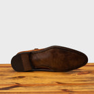 Outsole of Caramel leather shoe with Double buckle on a wooden surface