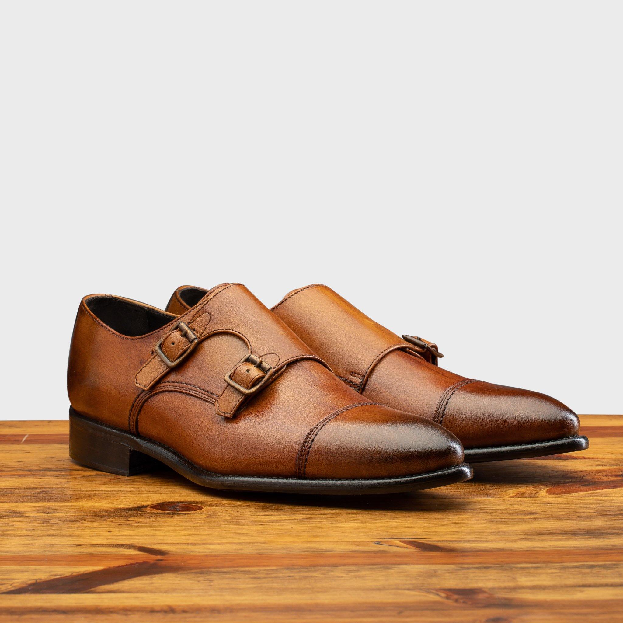 A Pair of Caramel leather shoe with Double buckle on a wooden surface