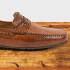 Brick leather loafer on a wooden surface with a white background