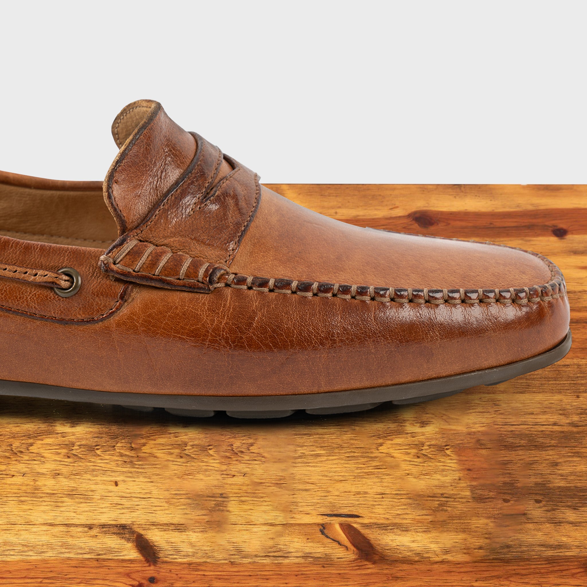 Brick leather loafer on a wooden surface with a white background