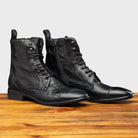 Pair of Black leather boot on a wooden surface with a light gray background