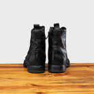Backside of Black leather boot on a wooden surface with a light gray background