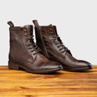 Pair of Brown leather boot on a wooden surface with a light gray background