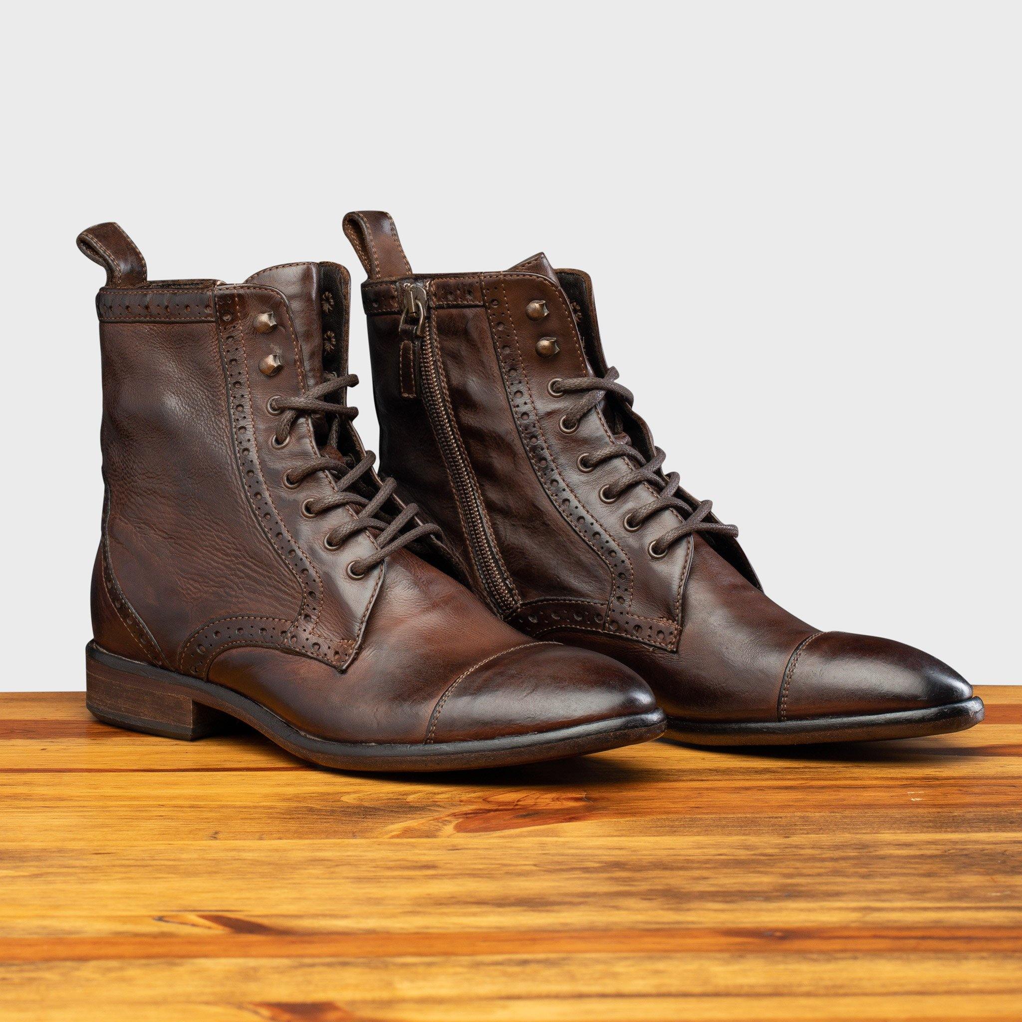 Pair of Brown leather boot on a wooden surface with a light gray background