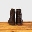 Back view of Brown leather boot on a wooden surface with a light gray background