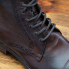 Close view of Brown leather boot on a wooden surface