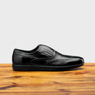 Black leather shoe on a wooden surface with a light gray background