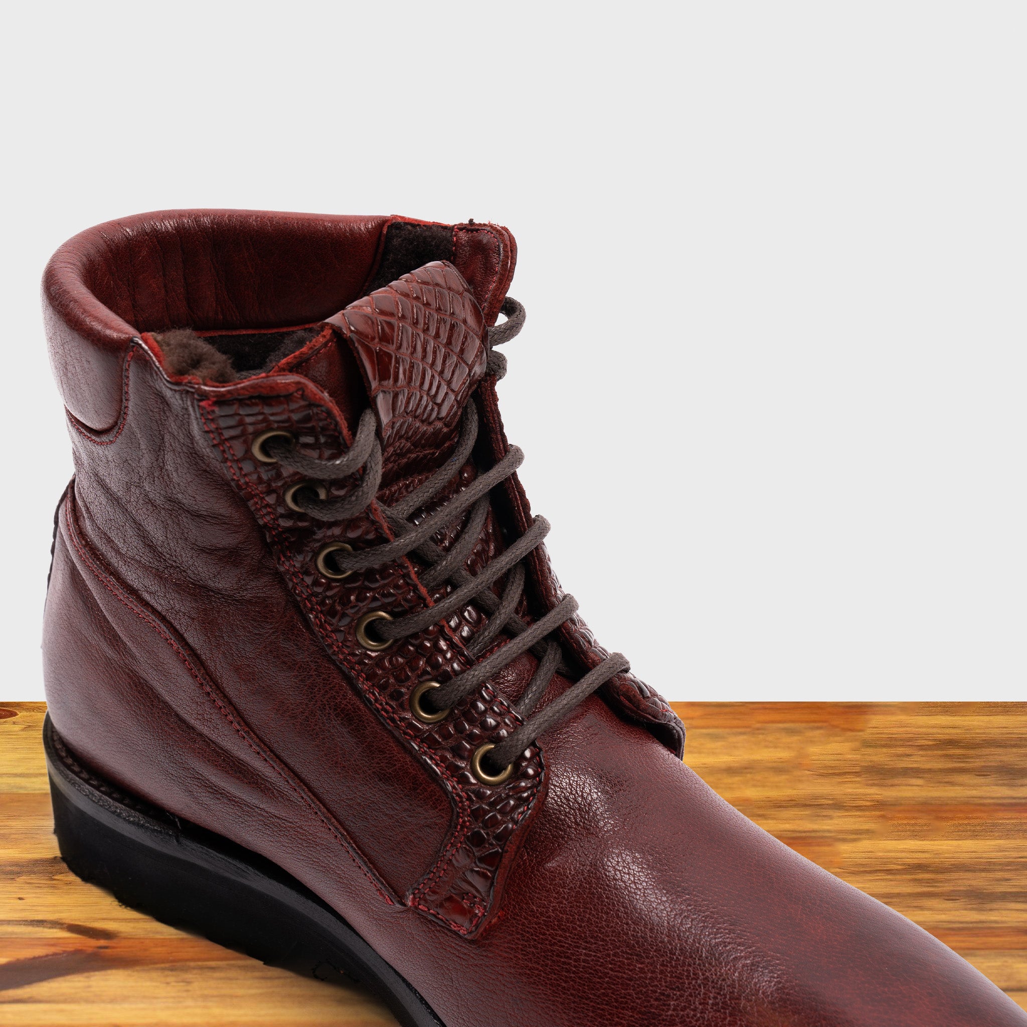 Cherry leather boots on a wooden surface
