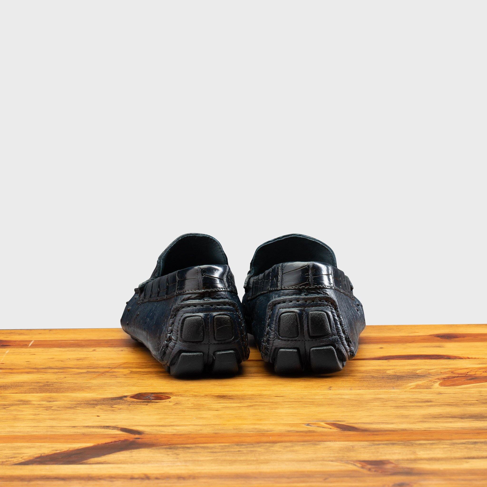 Back view of Blue leather loafer on a wooden surface with a light gray background