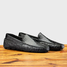 Pair of Black leather loafer on a wooden surface with a light gray background