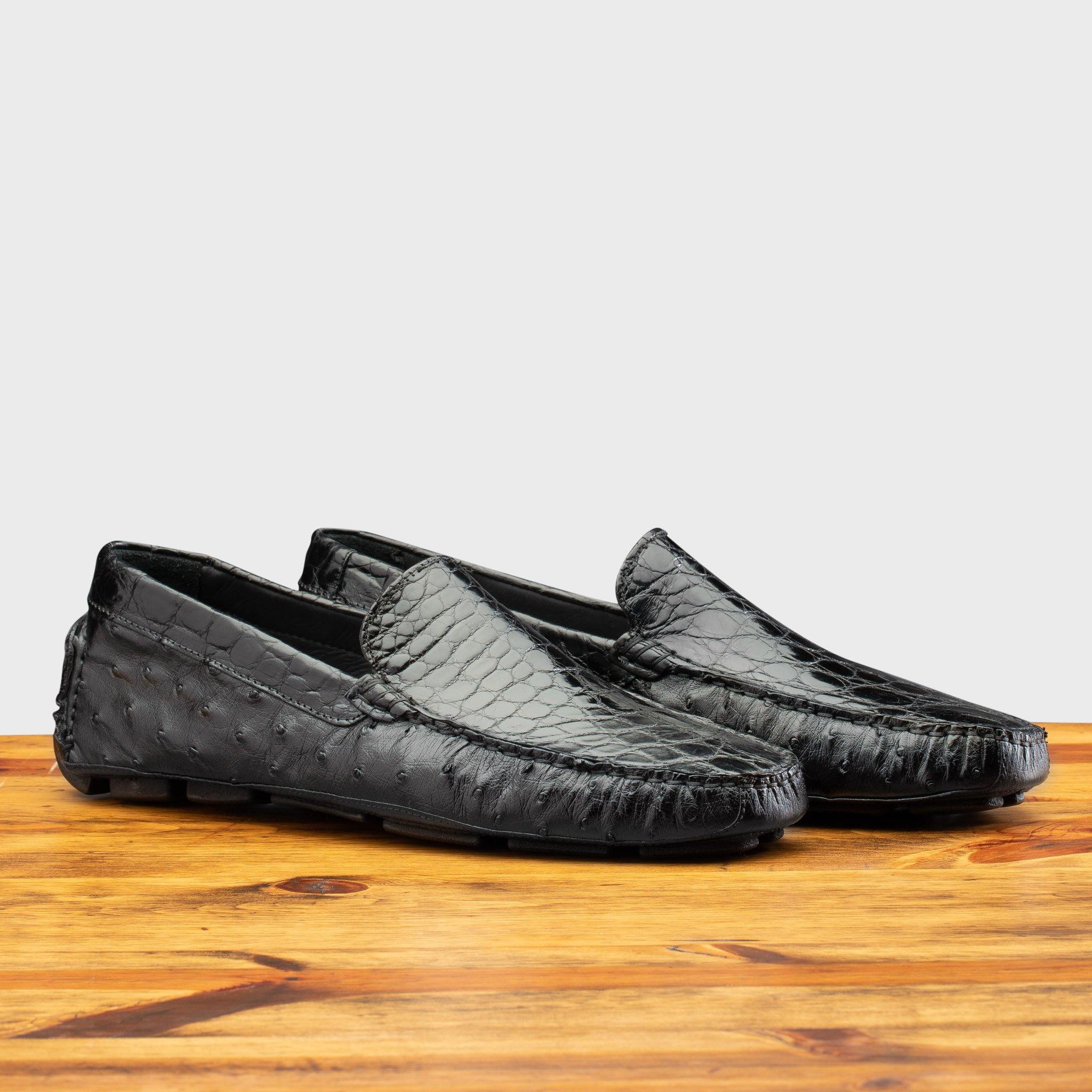 Pair of Black leather loafer on a wooden surface with a light gray background