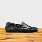 Black leather loafer on a wooden surface with a light gray background