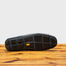 Outsole of Blue leather loafer on a wooden surface with a light gray background
