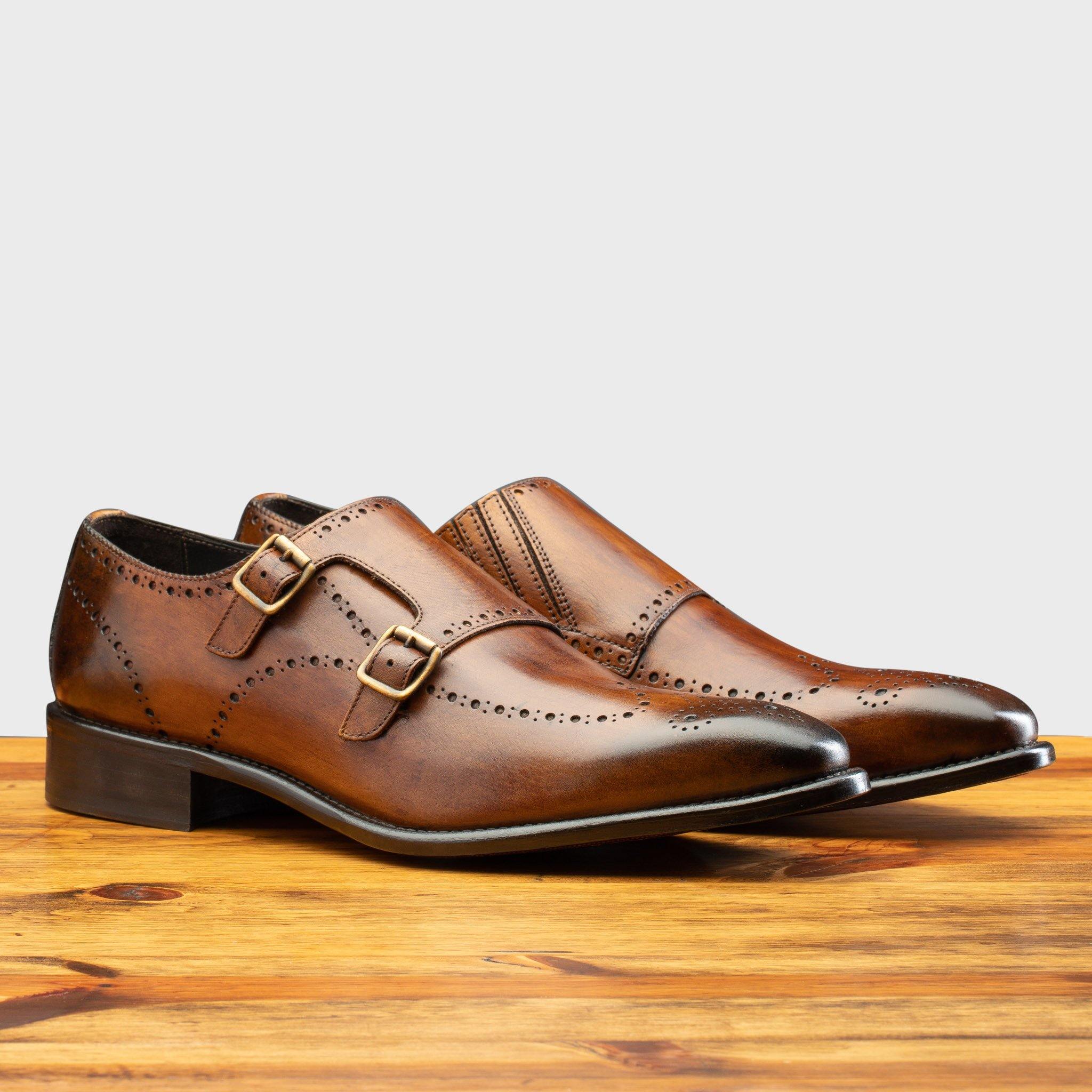A Pair of Brown leather dress shoe with gold buckle on a wooden surface