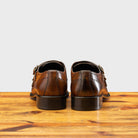 A Pair of Brown leather dress shoe with gold buckle on a wooden surface