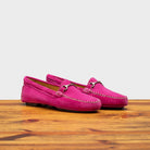 Pair of pink loafers on a wooden surface with a white background