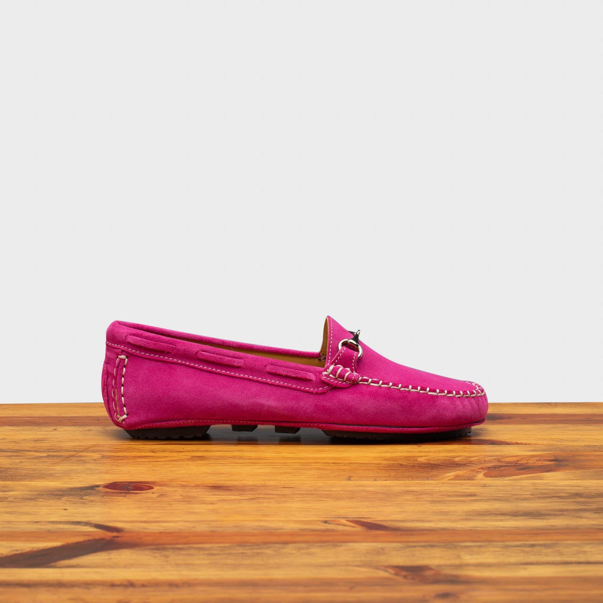 Pink loafers on a wooden surface with a white background