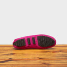 Outsole of pink loafers on a wooden surface with a white background