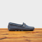 Blue velour suede driver shoes with a metallic bit, placed on a wooden surface.