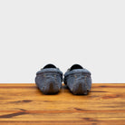 Back side of blue velour suede driver shoes with a metallic bit, placed on a wooden surface.