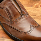 Brown leather shoe on a wooden surface
