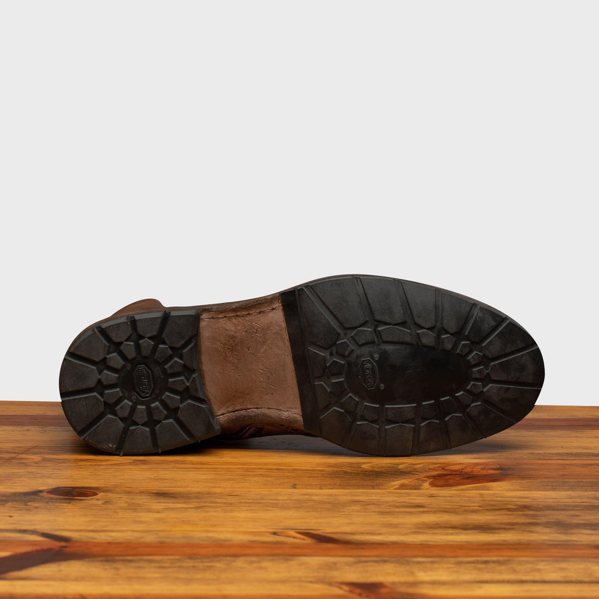Outsole of Moor leather boots on a wooden surface with a light gray background