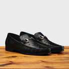 Pair of Black leather loafer on a wooden surface with a light gray background