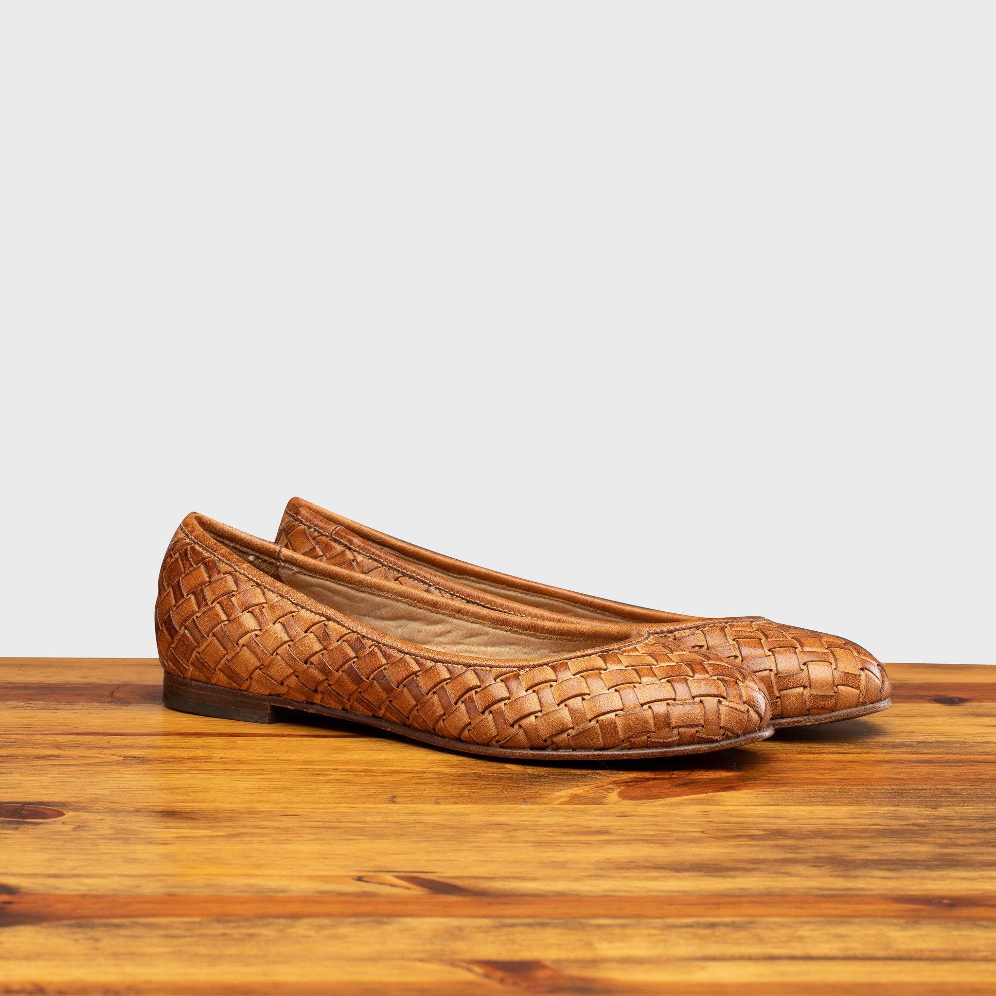 Pair of Brick woven flat shoe on a wooden surface with a light gray background