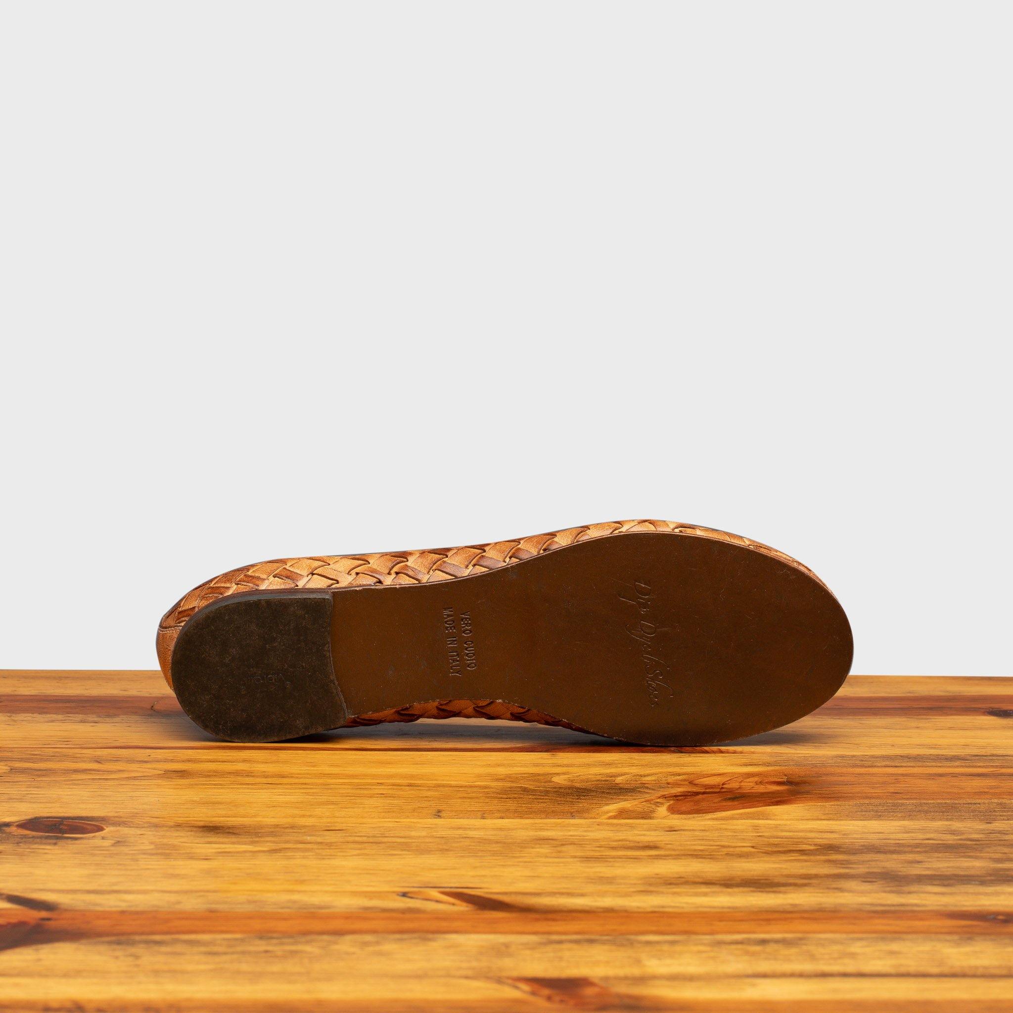 Outsole of Brick woven flat shoe on a wooden surface with a light gray background