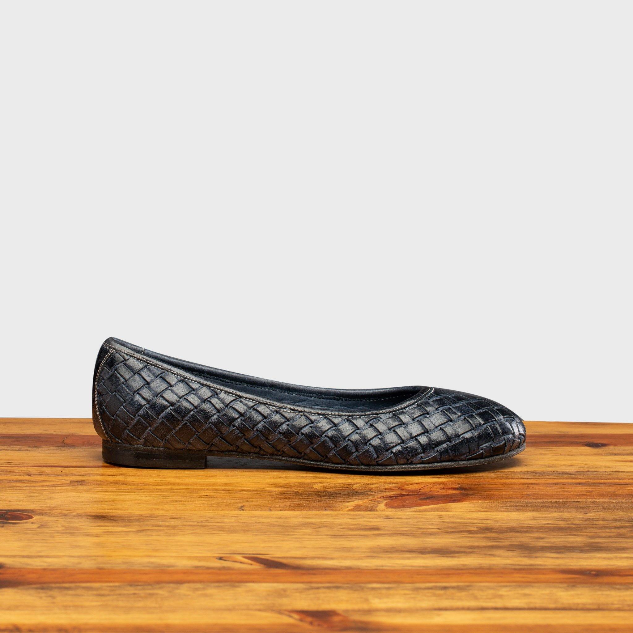 Navy Blue woven flat shoe on a wooden surface with a light gray background