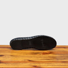 Outsole of Navy Blue woven flat shoe on a wooden surface with a light gray background