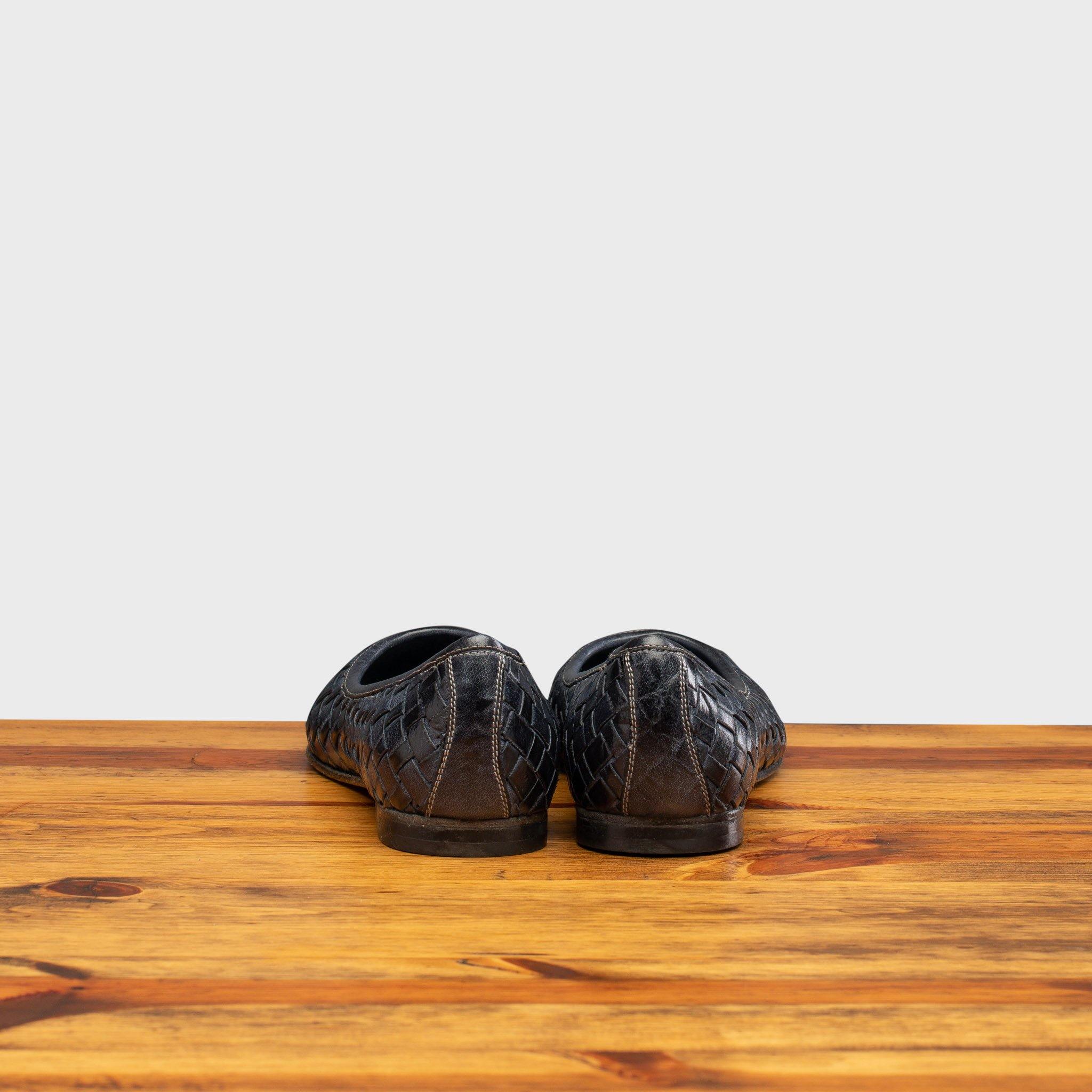 Back Side of Navy Blue woven flat shoe on a wooden surface with a light gray background