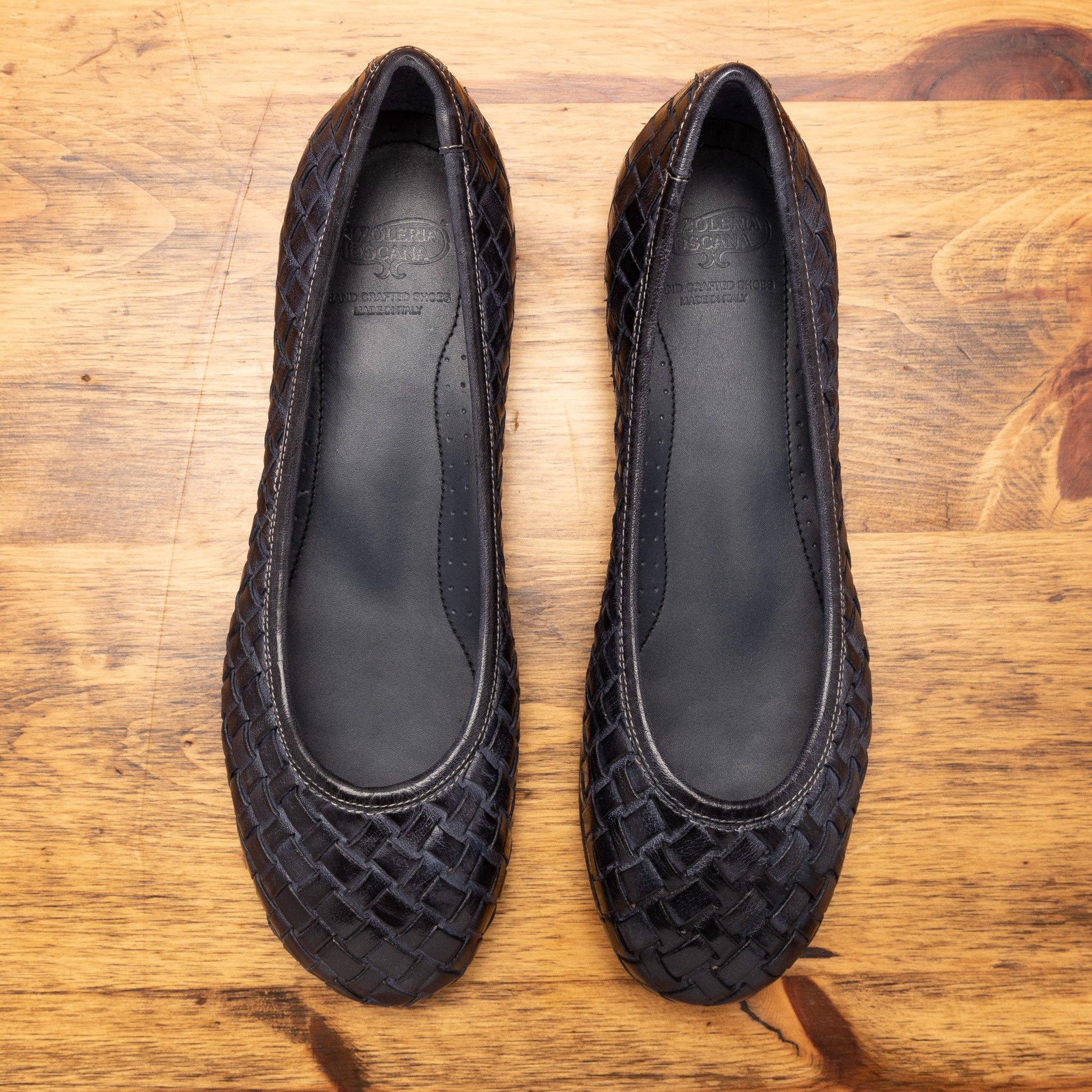 Pair of Navy Blue woven flat shoe on a wooden surface