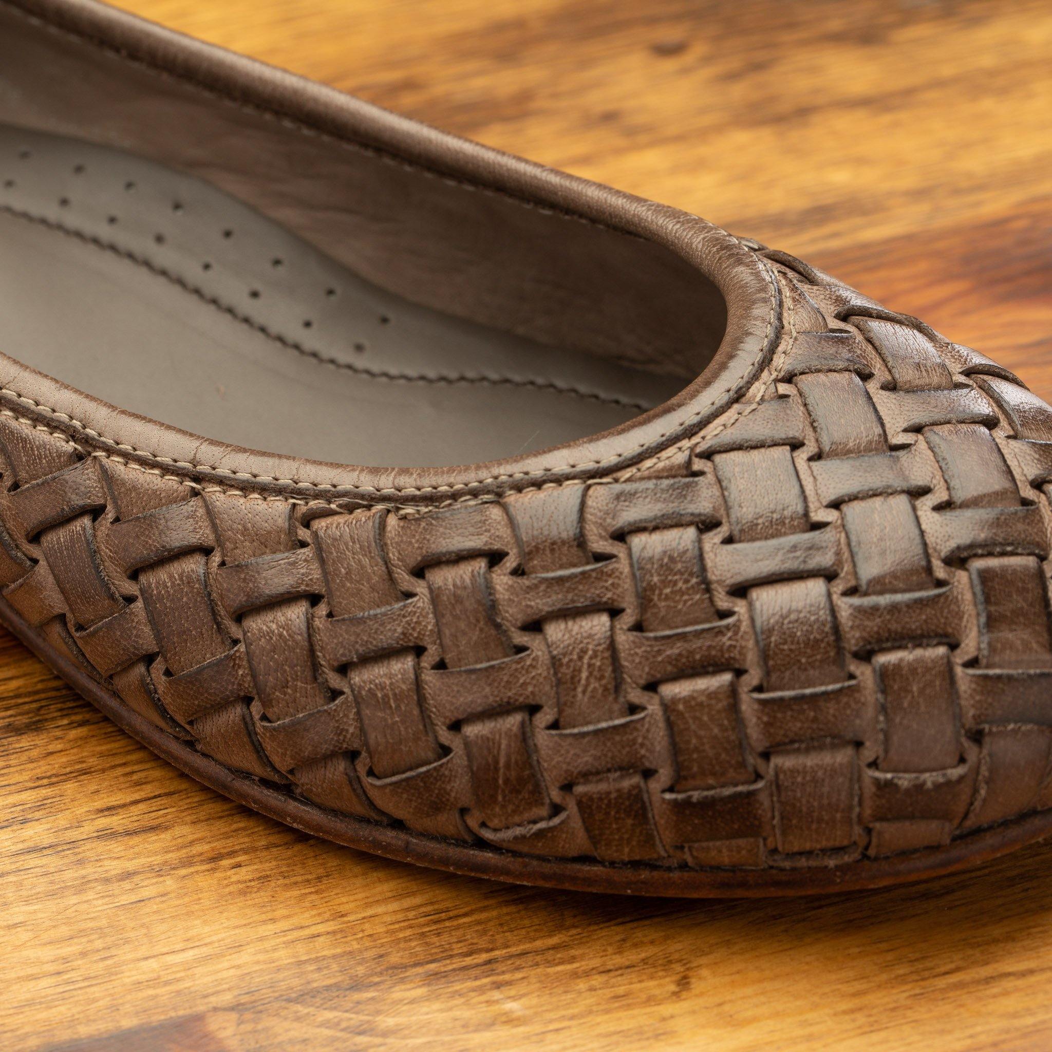 Close view of Taupe woven flat shoe on a wooden surface

