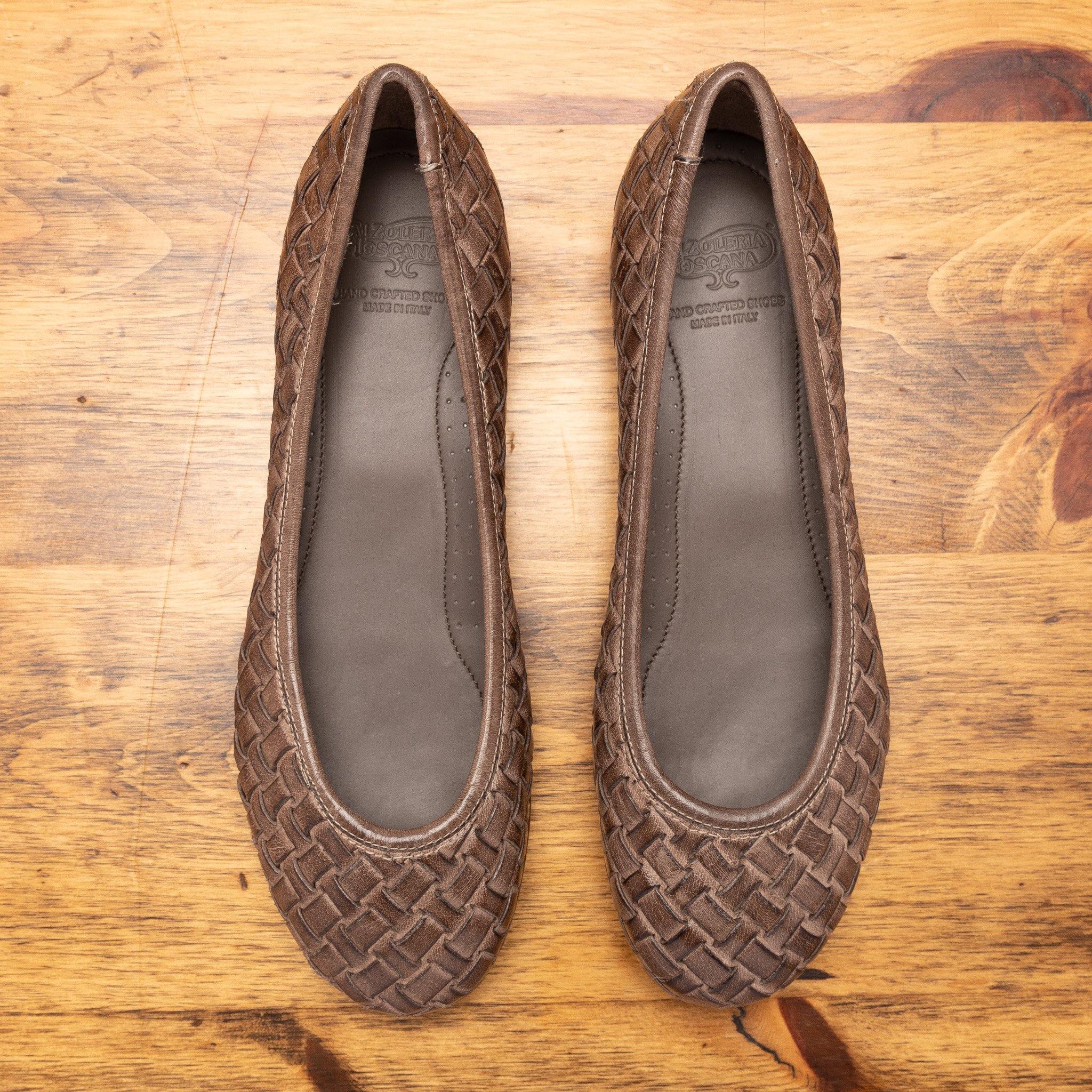 Pair of Taupe woven flat shoe on a wooden surface