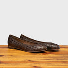 Pair of Tobacco woven flat shoe on a wooden surface with a light gray background