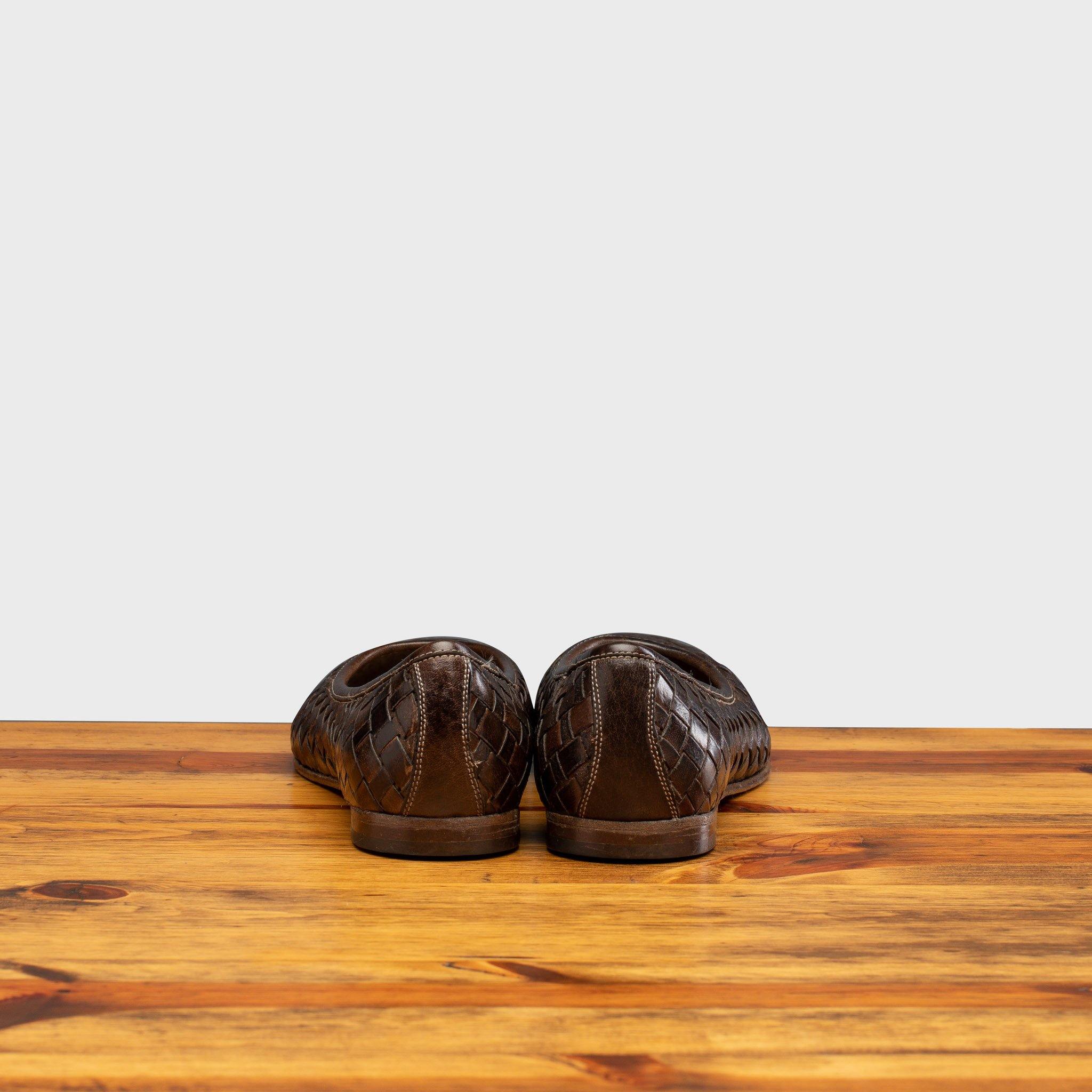 Back Side of Tobacco woven flat shoe on a wooden surface with a light gray background